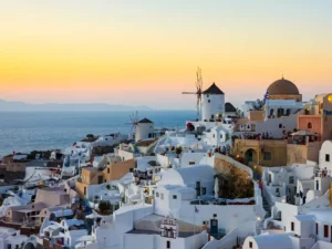 טחנת רוח בכפר אויה באי סנטוריני ובתים לבנים על רקע השקיעה האגאית