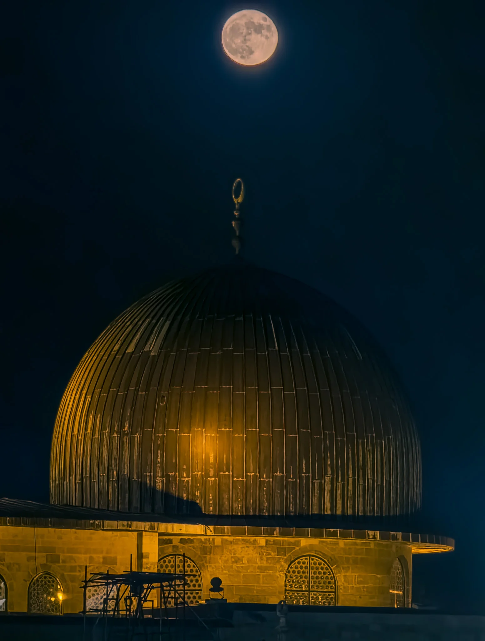 ירח מלא מאיר את שמי הלילה מעל מבנה כיפה עתיק, על רקע העיר העתיקה של ירושלים