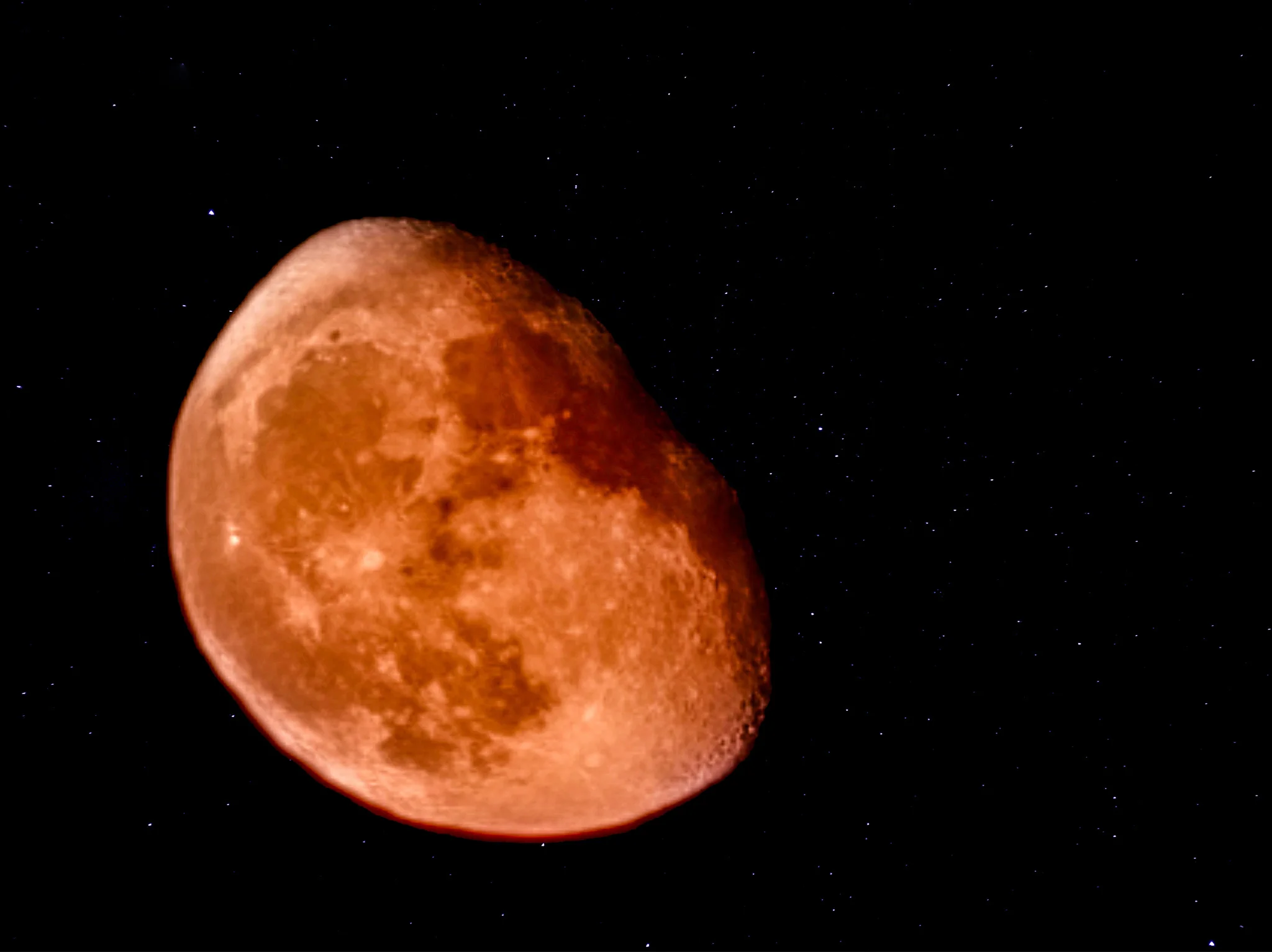 ליקוי ירח דם שובה לב עם גוון אדמדם על רקע שמי לילה עטורי כוכבים